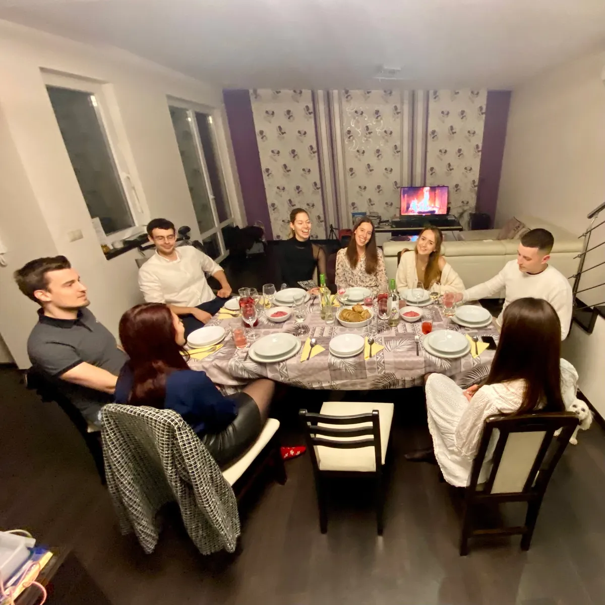 Tizenkét vendég egy hosszú vacsoraasztal körül egy lakásvacsorán